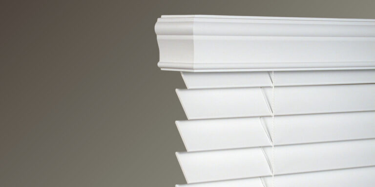 Window blinds with a valance header in a living room.